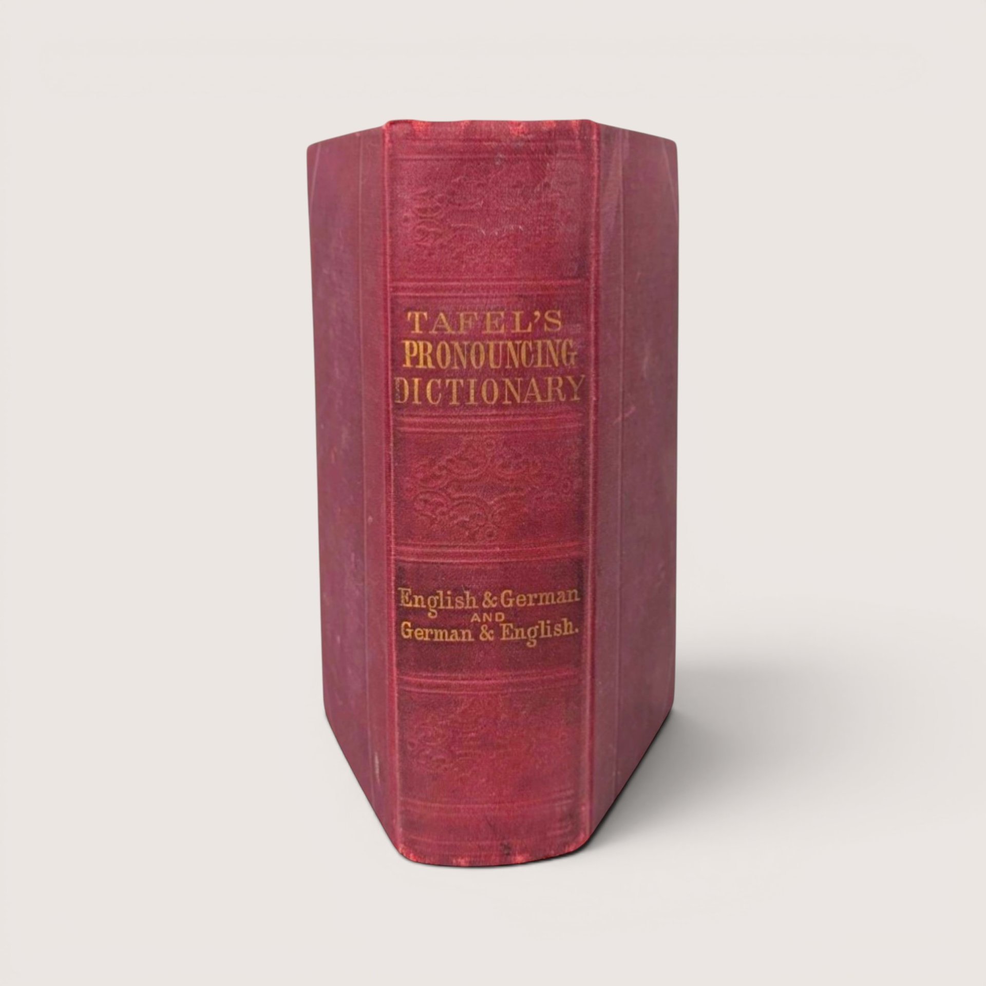 An antique 1870 hardcover pocket dictionary with a worn red cloth spine and gold gilt lettering.