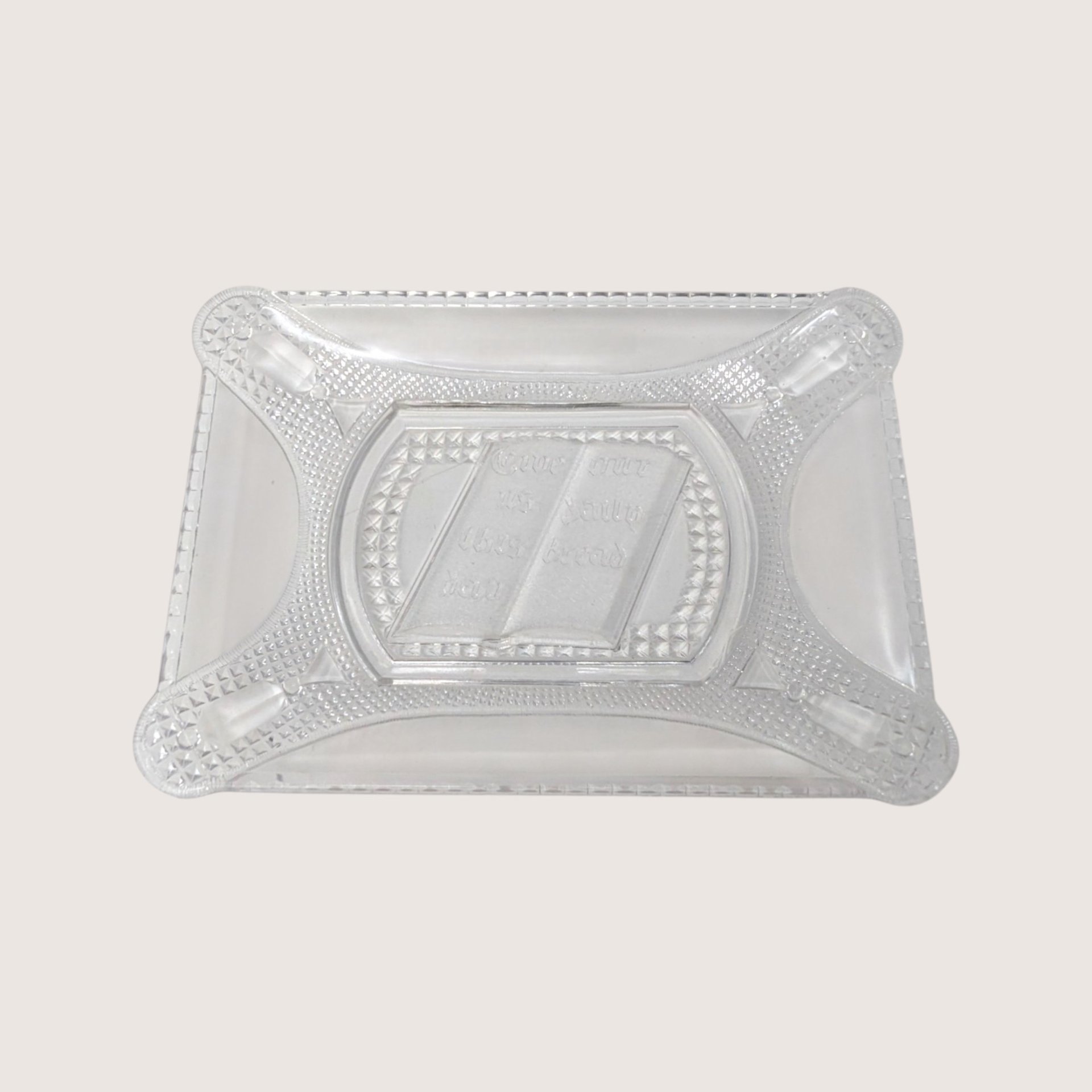 Antique rectangular clear pressed glass bread plate featuring an embossed open Bible text on a solid cream backdrop.