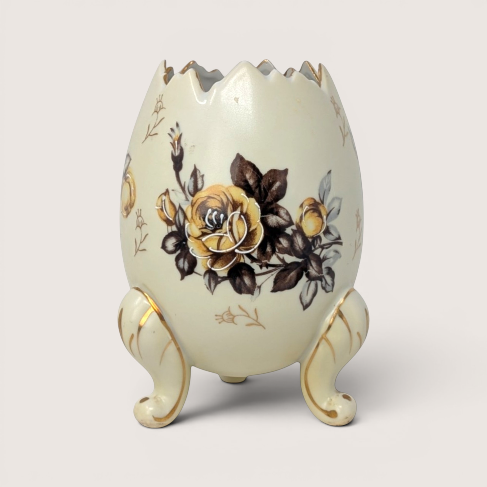 Vintage cream-colored cracked egg ceramic vase with yellow rose transfer designs standing on three gold-trimmed feet.