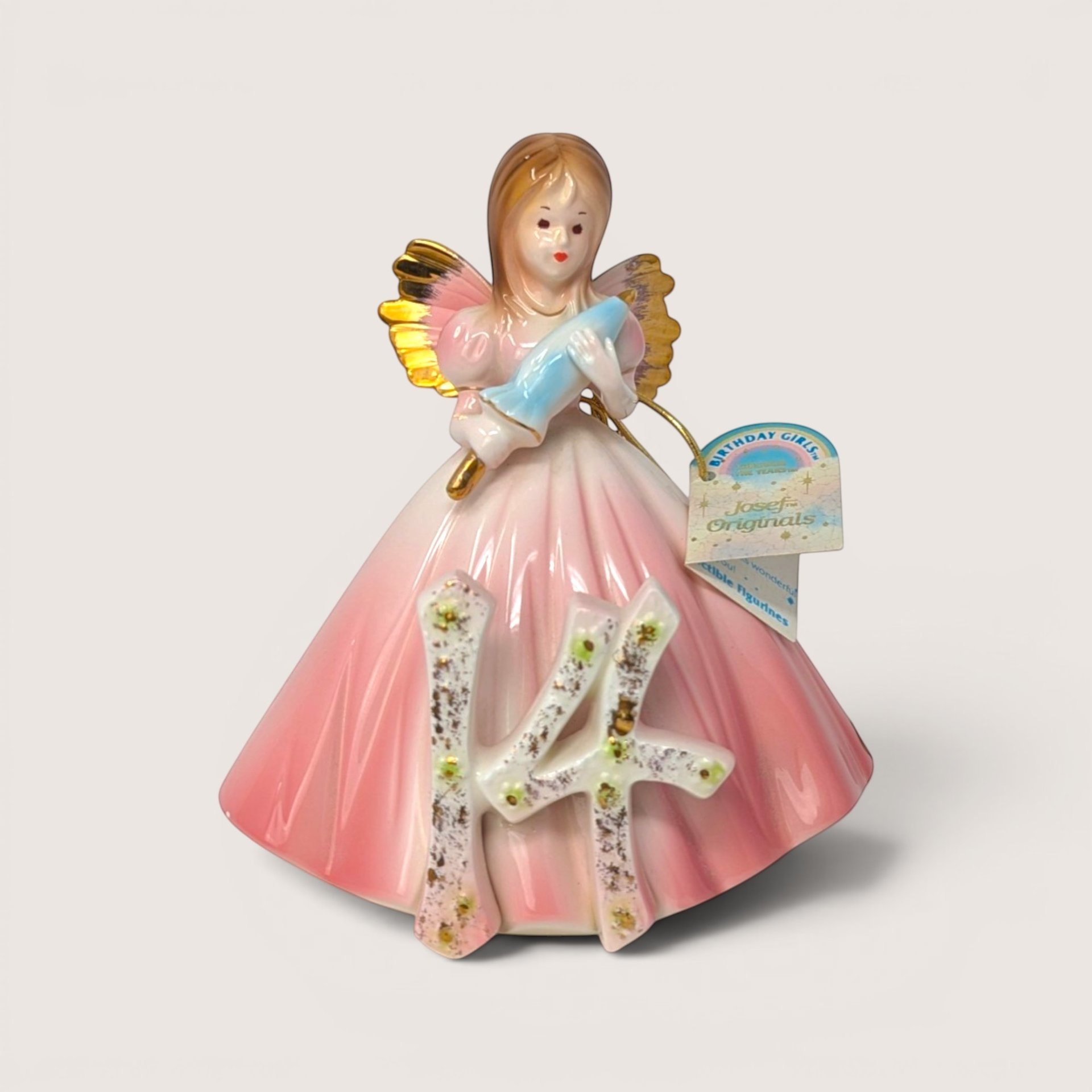 Vintage Josef Originals age 14 birthday girl porcelain figurine holding a blue parasol on a linen background.