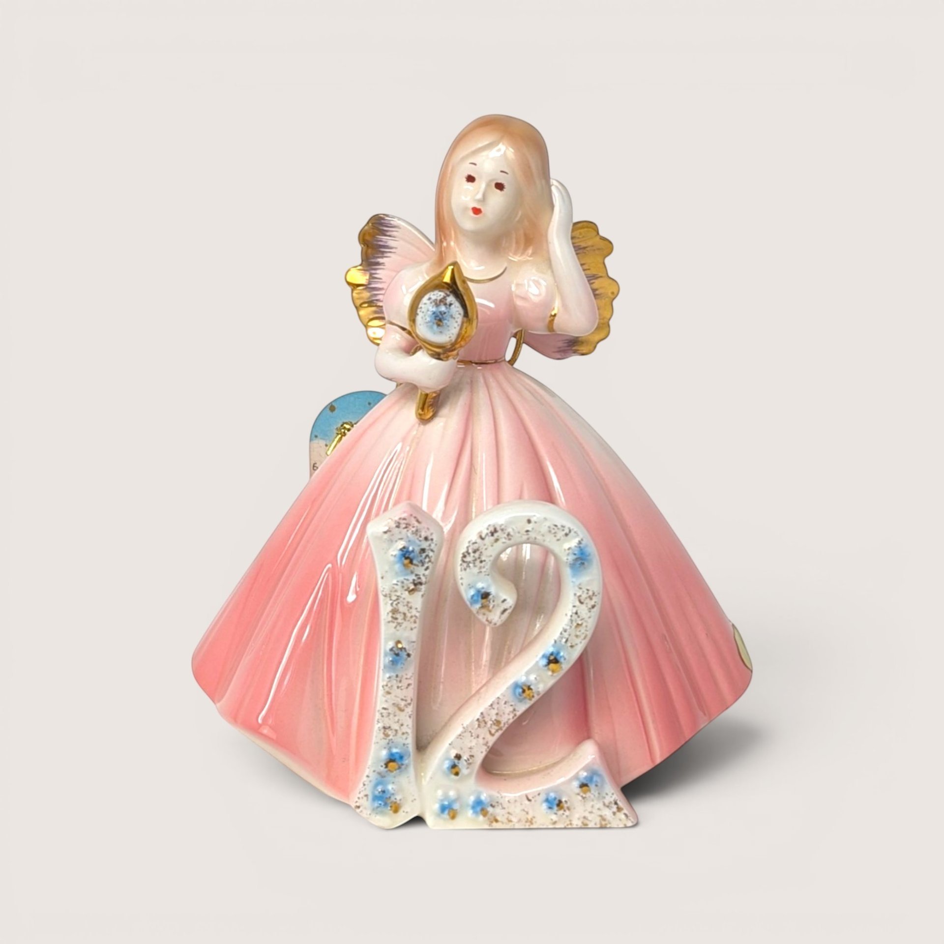 Vintage Josef Originals age 12 birthday girl porcelain figurine holding a gold hand mirror on a linen background.