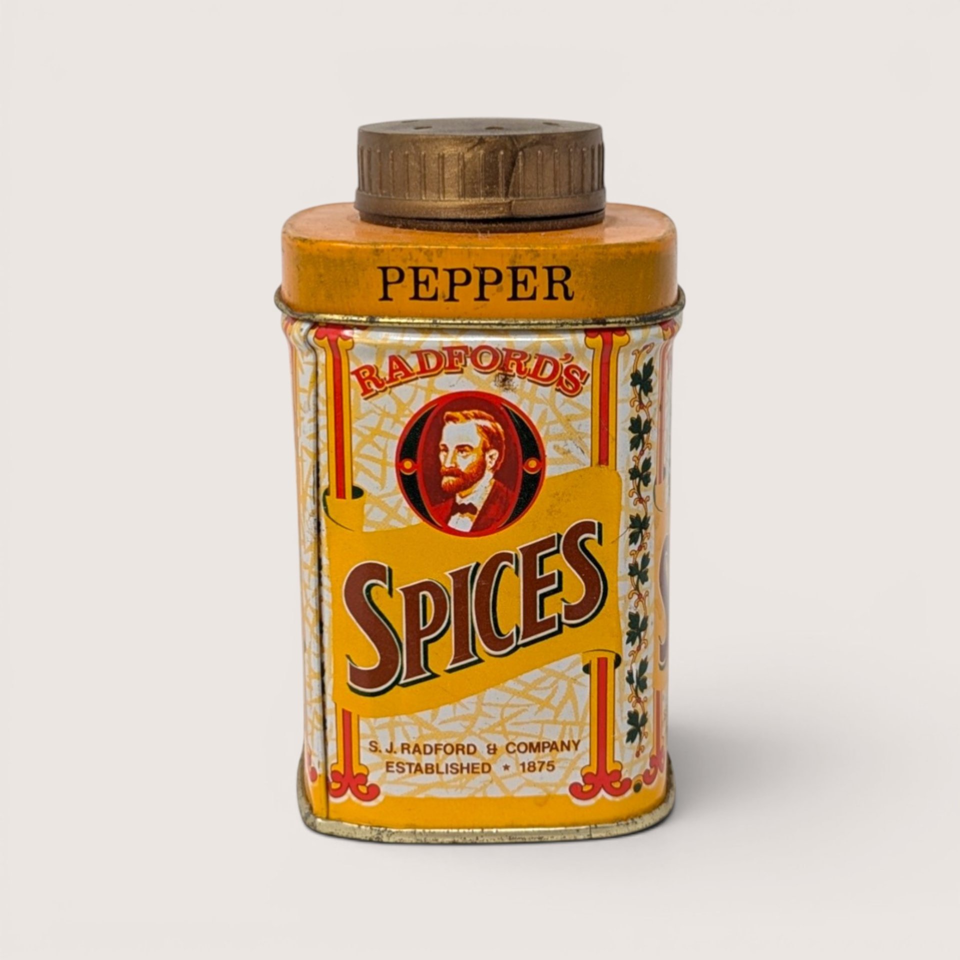 A small yellow vintage spice tin featuring a man portrait and a gold shaker cap on a plain white background