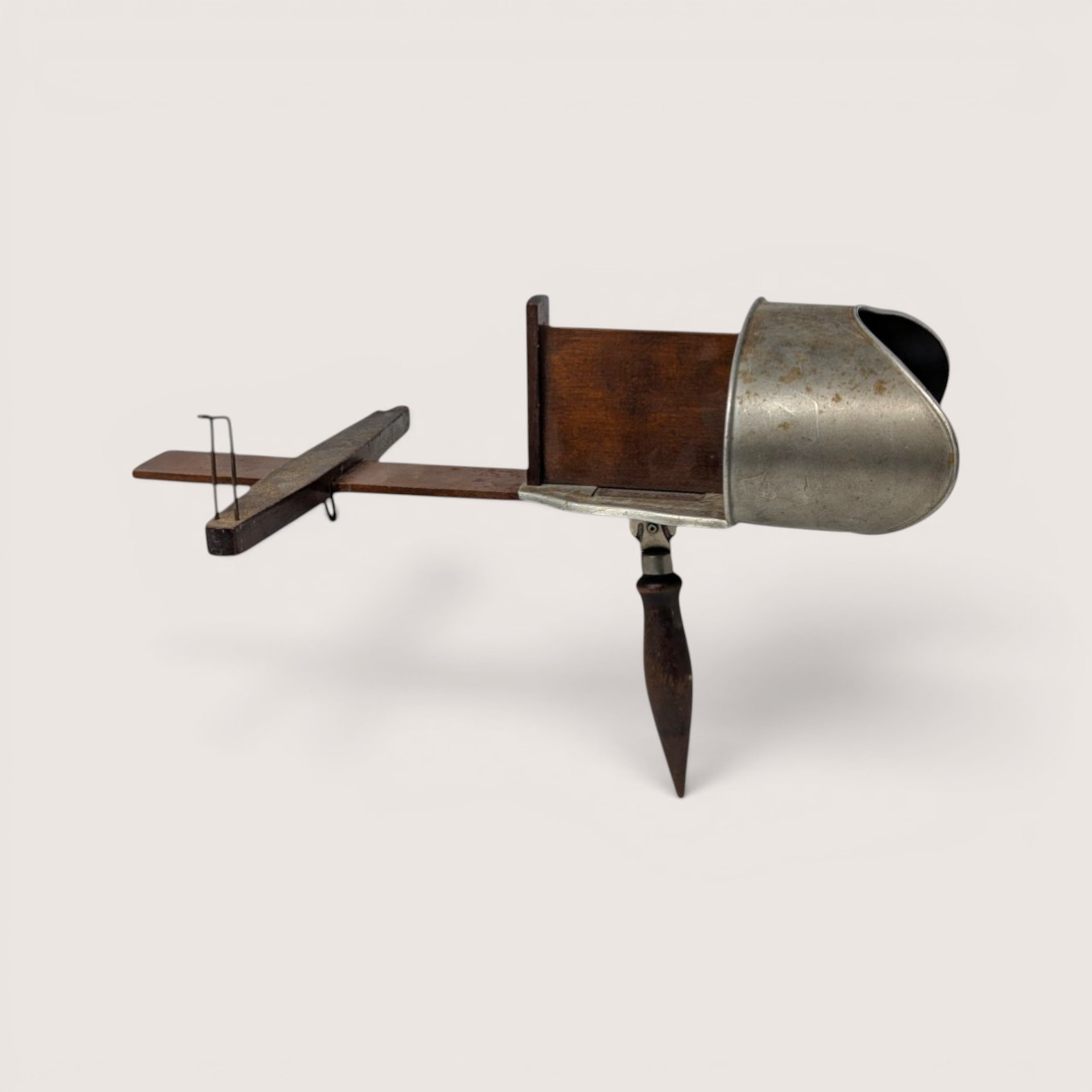 An antique hand-held stereoscope viewer constructed of wood and aluminum on a plain light background