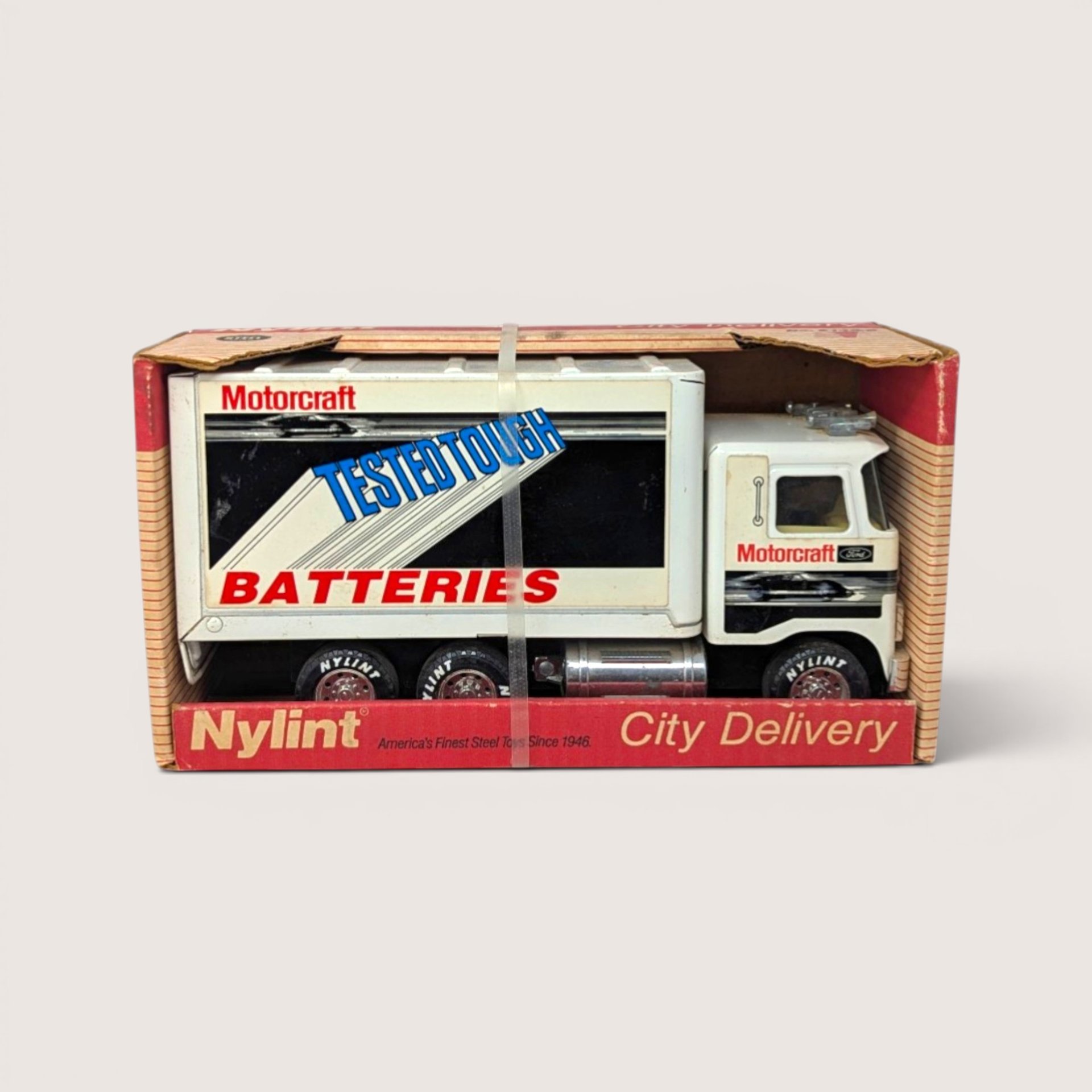 Vintage 1980s white Nylint Ford pressed steel City Delivery box truck featuring Motorcraft Batteries advertising in original box.