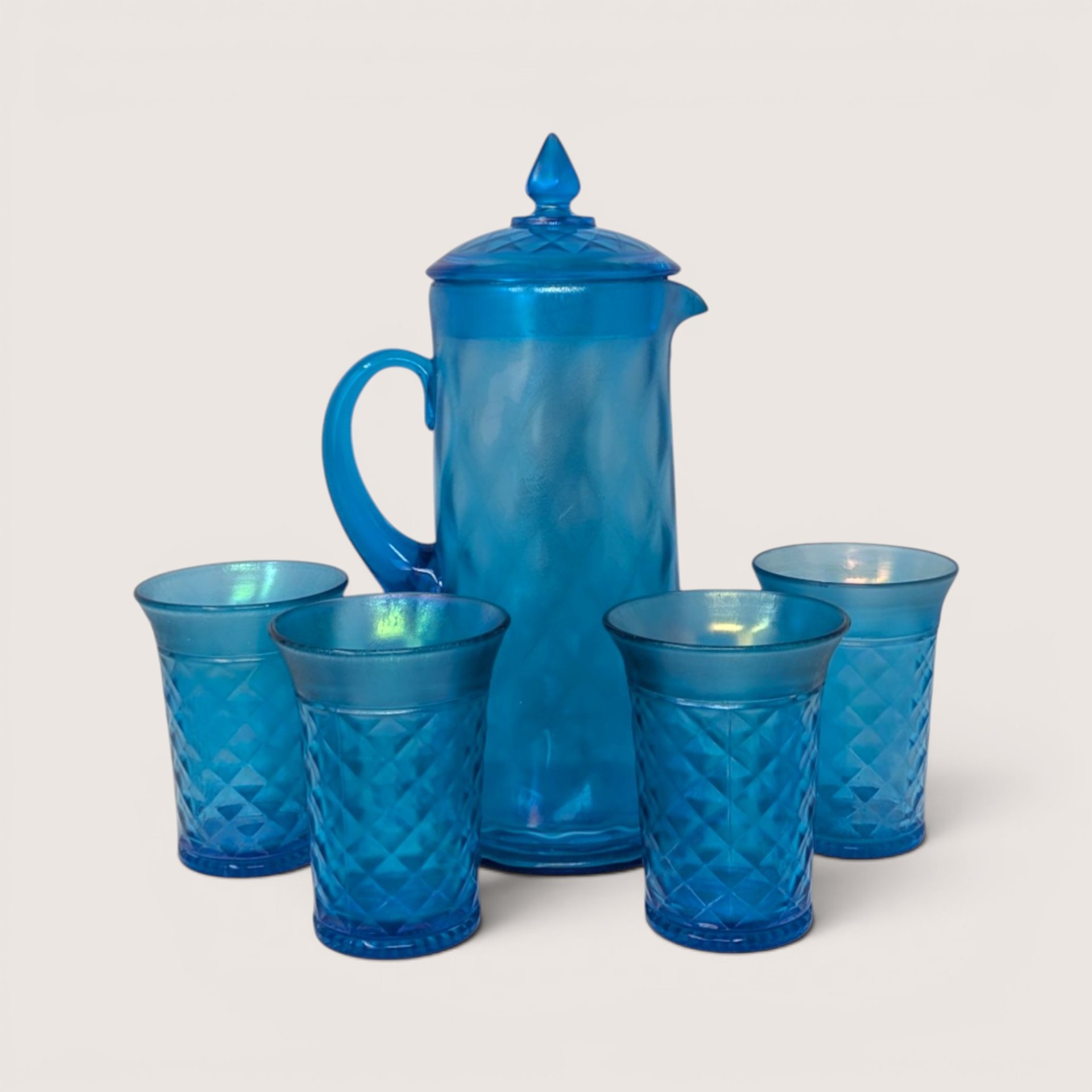 Antique Northwood celeste blue iridescent stretch glass pitcher with a matching lid surrounded by four tumblers.