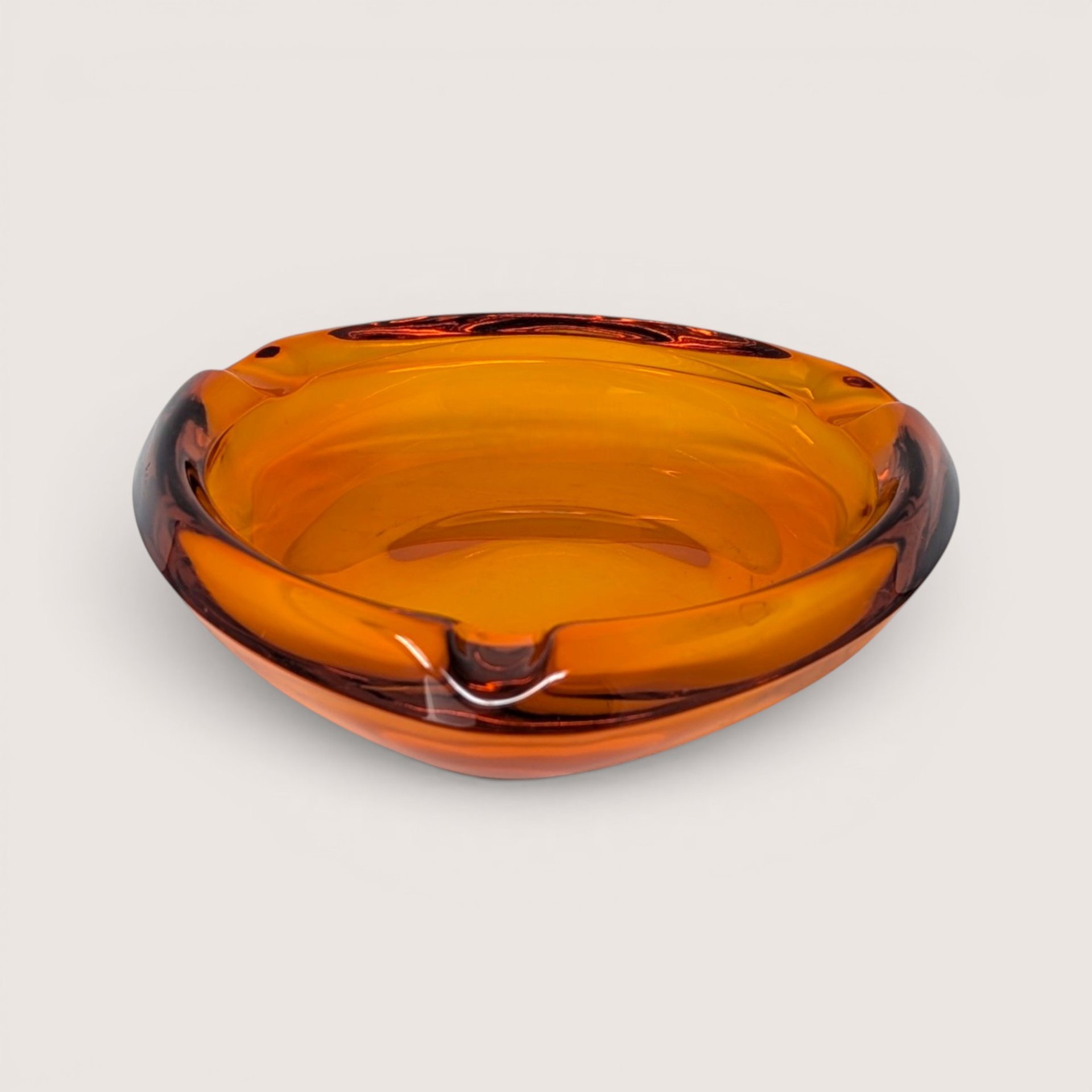 Vintage 1960s Viking Glass heavy honey amber art glass ashtray with a smooth asymmetrical shape.