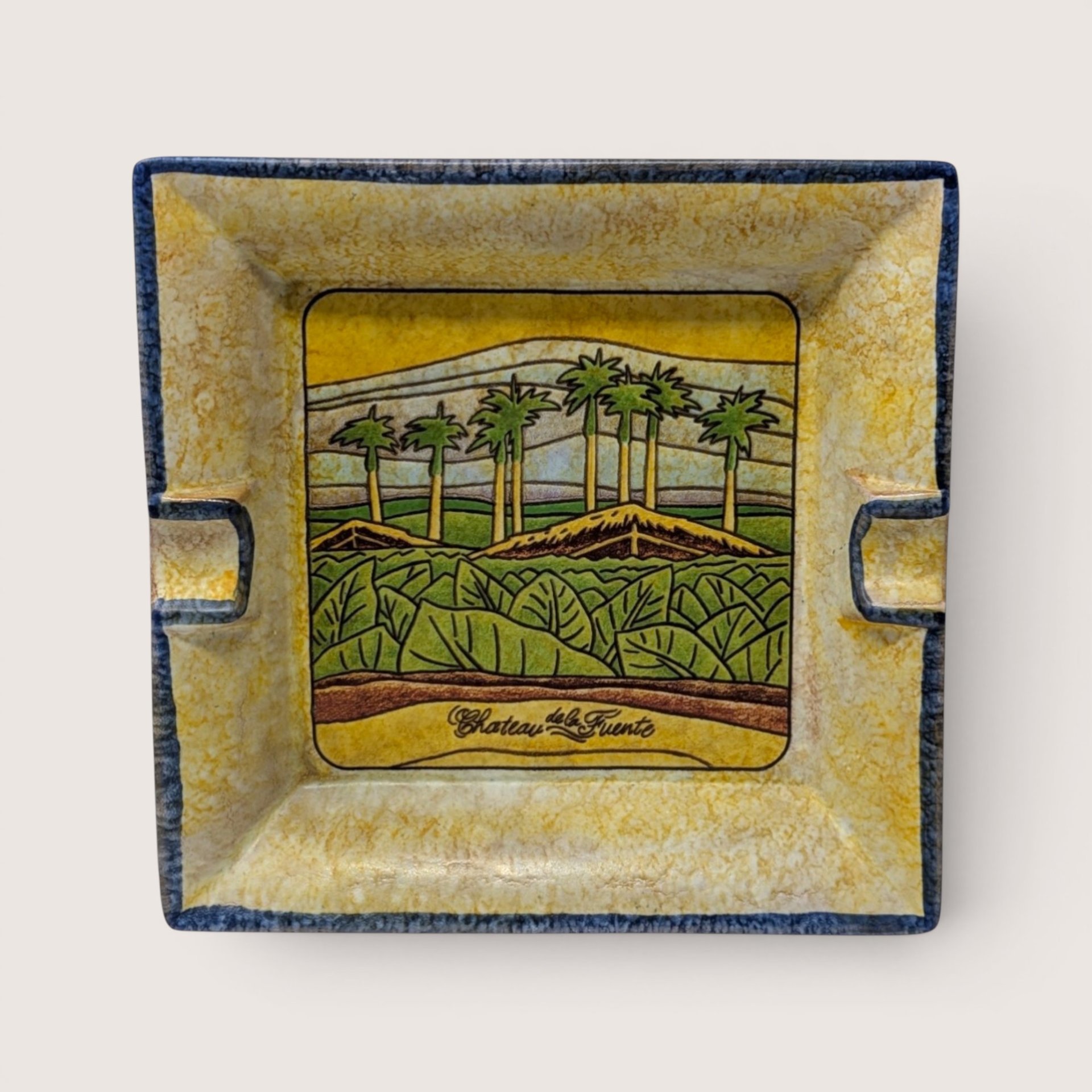 Square hand painted ceramic ashtray featuring a tobacco field with palm trees and Chateau de la Fuente script.