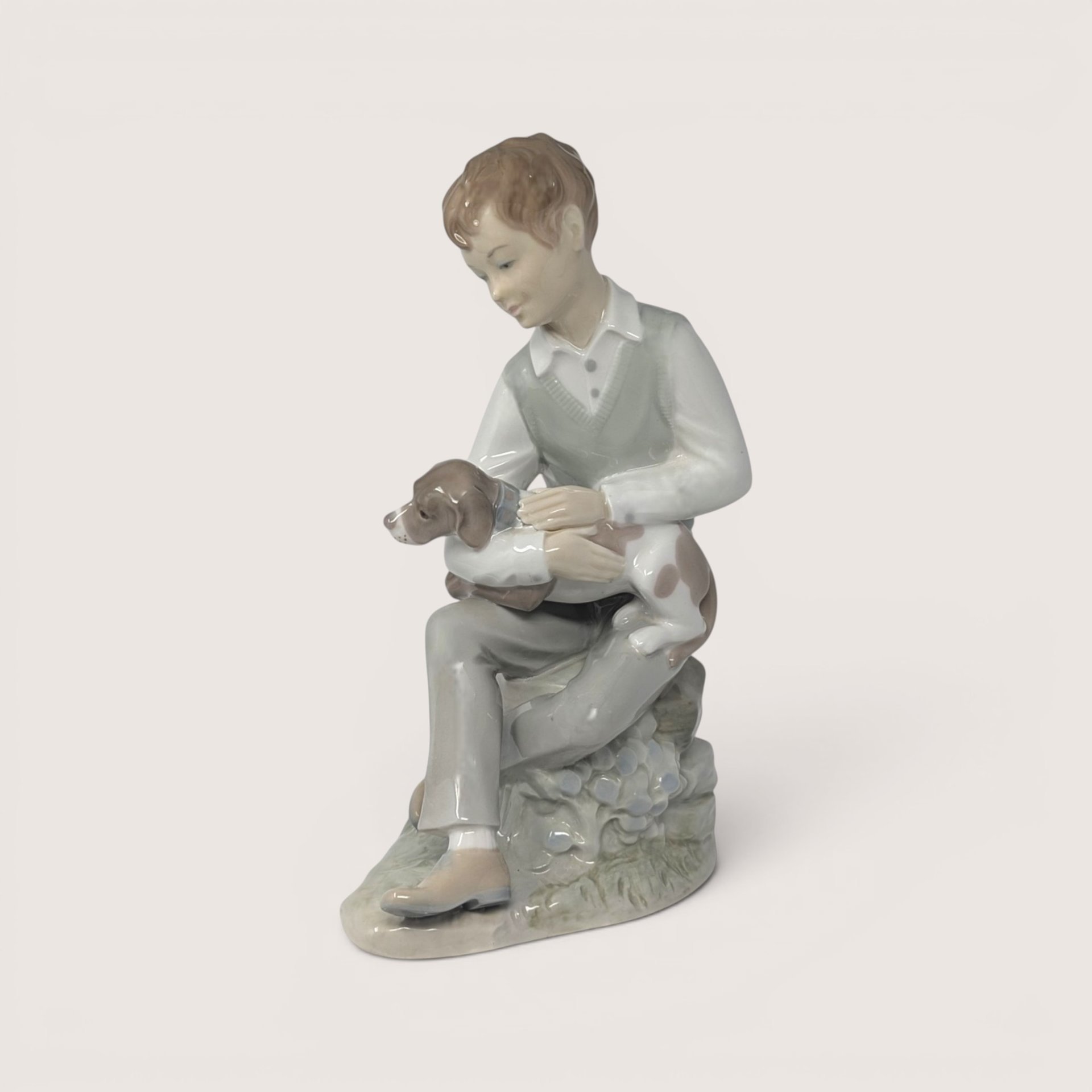 Vintage Zaphir porcelain figurine of a young boy sitting and petting a spotted puppy.