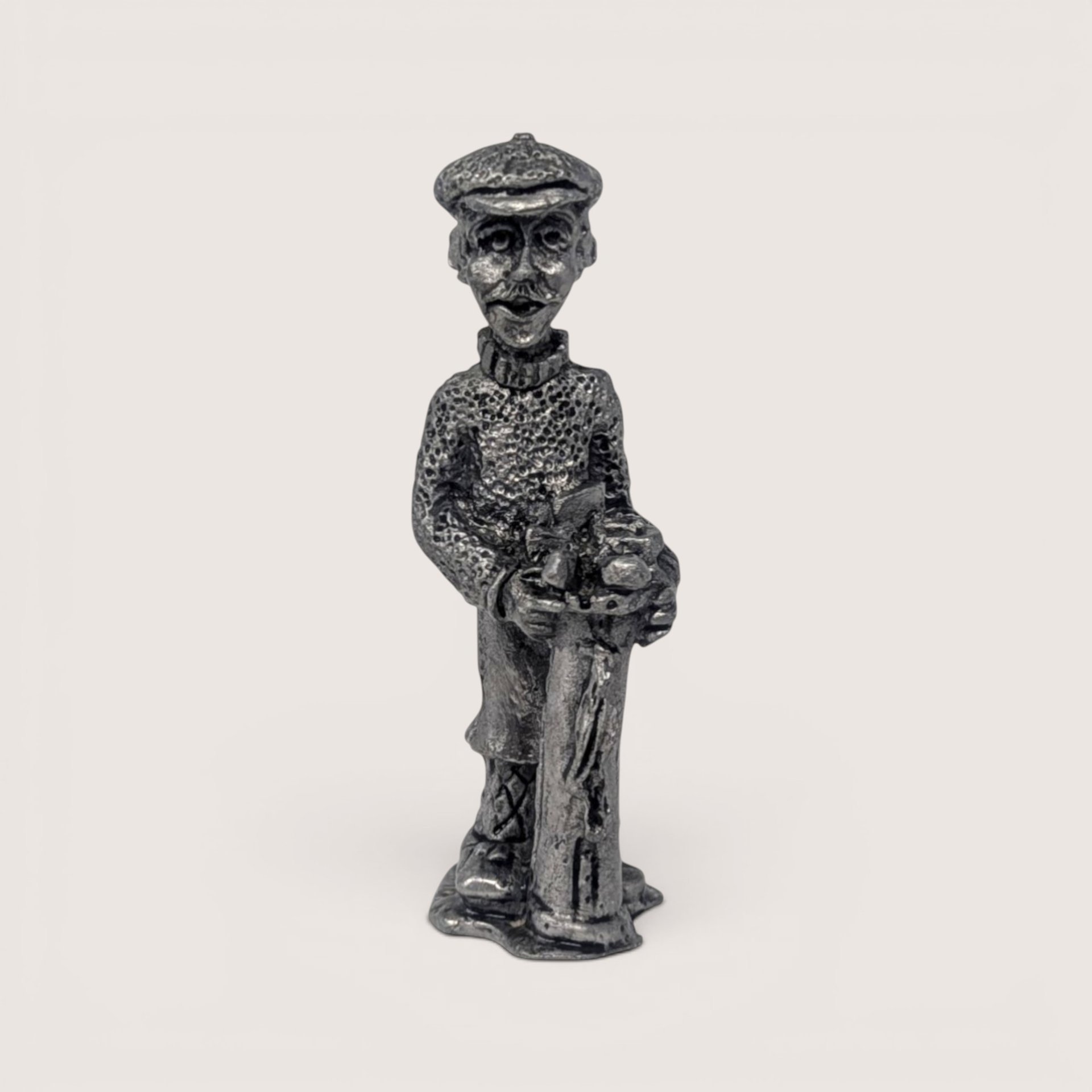Vintage handcrafted pewter golfer figurine wearing a patterned sweater and cap while holding vintage golf clubs.