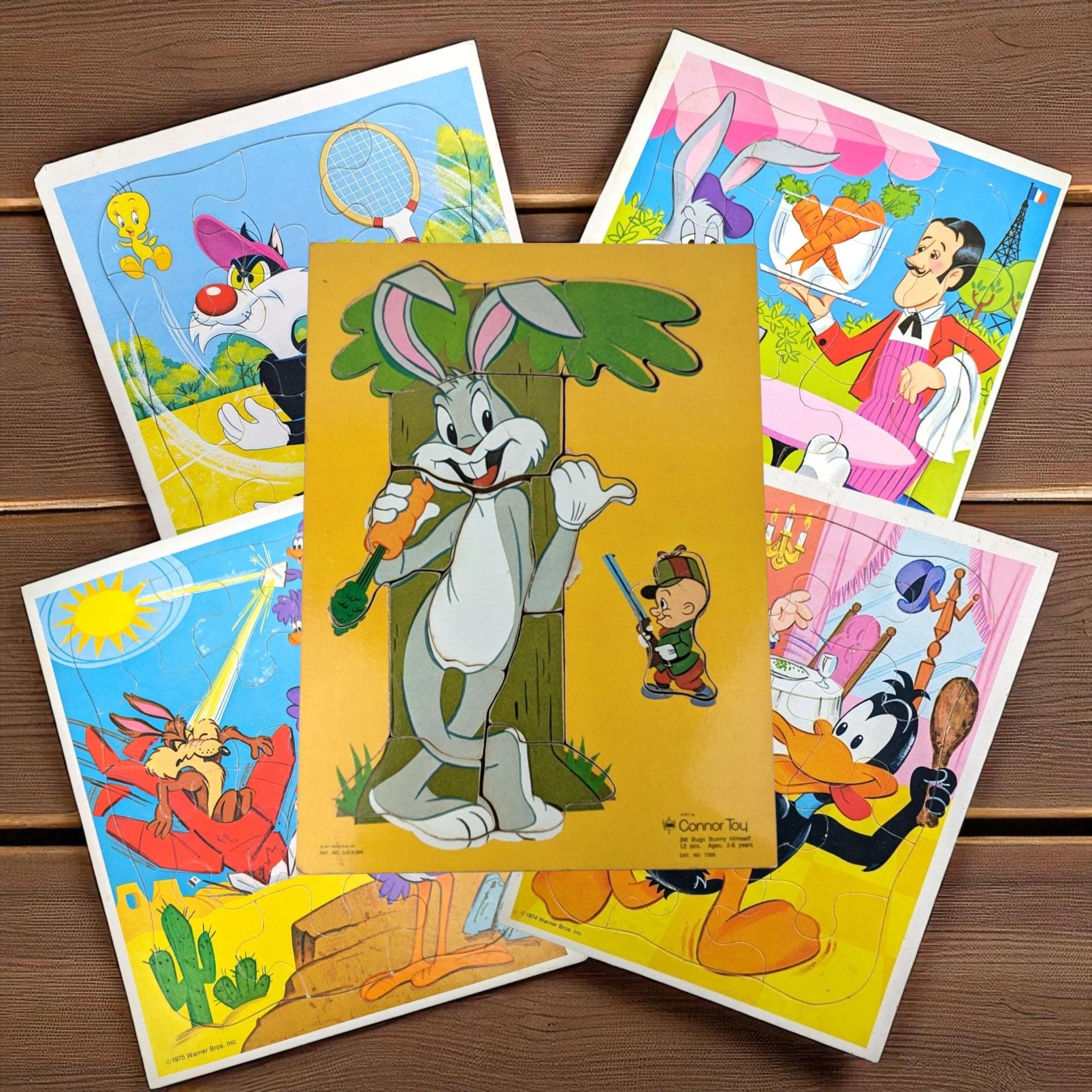 Four vintage cardboard tray puzzles featuring various Looney Tunes characters. Each puzzle displays a distinct silhouette with vibrant, saturated colors against simple backgrounds. The surfaces show a slight textural sheen common to mid-century lithographed cardboard.