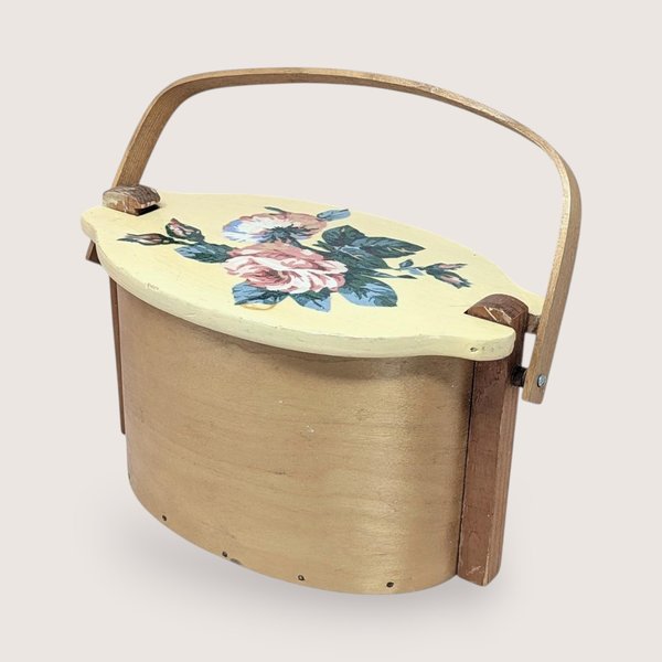 Vintage Basketville wood bucket with a swing handle and fitted lid. Features a hand-painted pink rose and blue floral bouquet on a cream-colored lid. Natural light wood finish. 11.5 inches long.