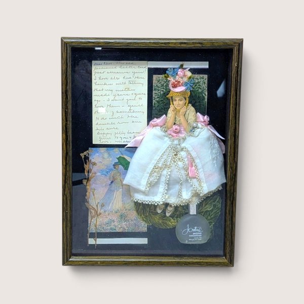 Vintage 1980s framed shadow box collage featuring a fabric doll figure with a lace dress and a Jontue perfume bottle