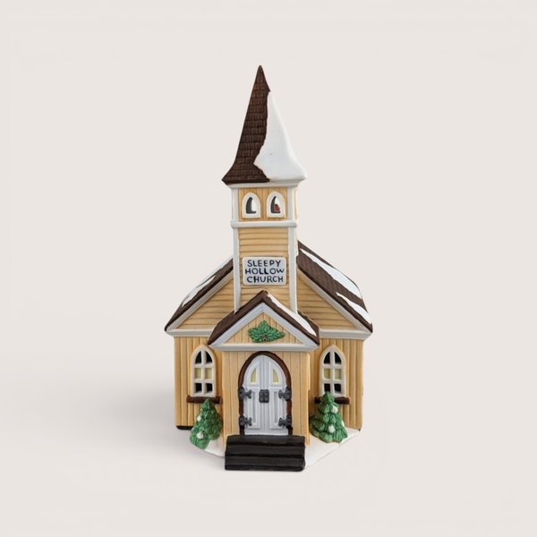 Hand-painted porcelain miniature Sleepy Hollow Church with a yellow facade, snow-dusted brown roof, and a tall steeple.