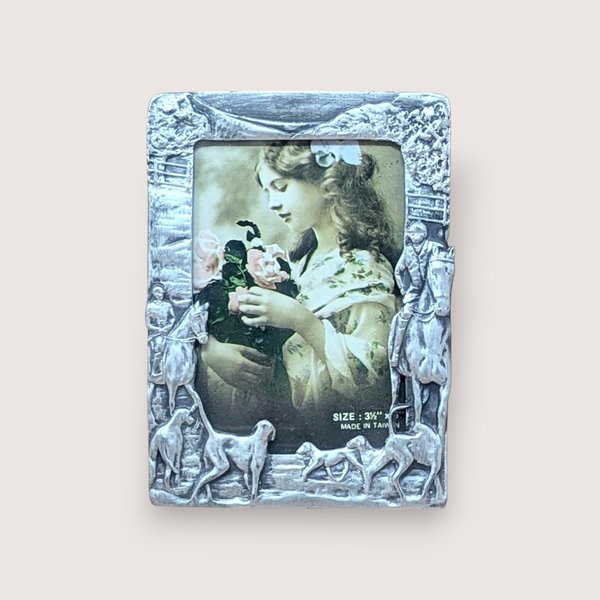A horizontal photo frame with a deep red enamel border. Ornate gold-tone decorations include a crystal-studded purple hibiscus-style flower on the top left and a fashionable stiletto shoe on the bottom right.