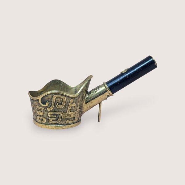 Vintage brass Chinese silk iron with an intricate textured pattern and a dark wooden handle, isolated on a light background.