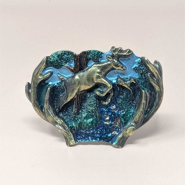 A vintage 1970s belt buckle with a leaping doe in enamel and brass-toned metal accents on a neutral background.