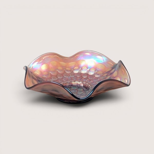 A vintage Fenton marigold carnival glass bowl with a ruffled edge and a dimpled coin dot pattern, showing iridescent pink and gold tones.