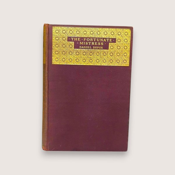 A plum-colored hardcover book with a large gold-stamped ornate panel on the front cover titled The Fortunate Mistress by Daniel Defoe against a neutral background.