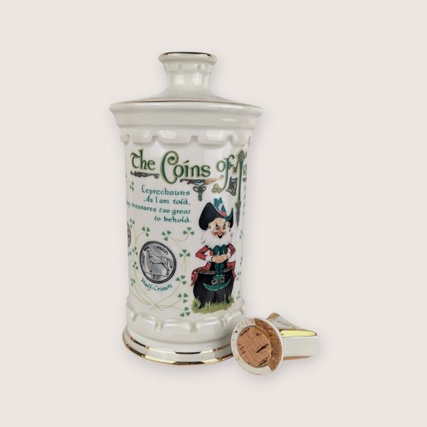 White ceramic Old Commonwealth Coins of Ireland empty decanter with leprechaun graphic and broken harp stopper.