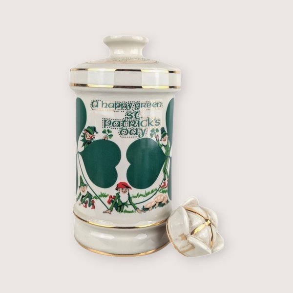 White ceramic Old Commonwealth Flowers of Ireland empty decanter with a green St Patricks Day graphic and broken stopper.