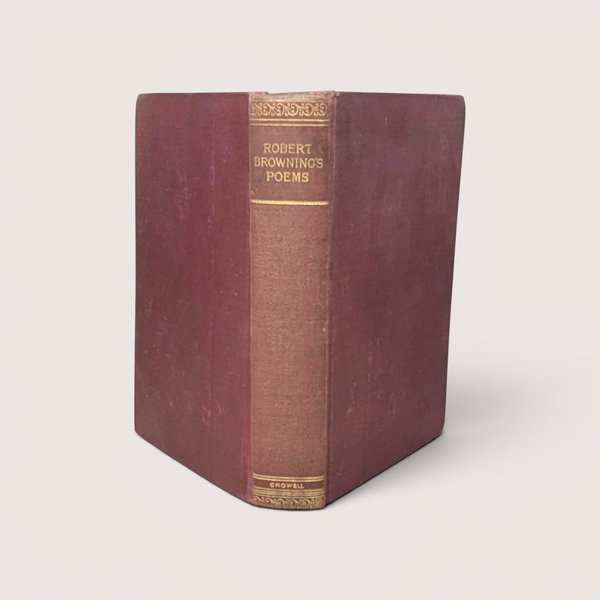 A burgundy cloth-bound hardcover book standing upright, featuring gilded typography on the spine for Robert Browning's Poems against a neutral background.