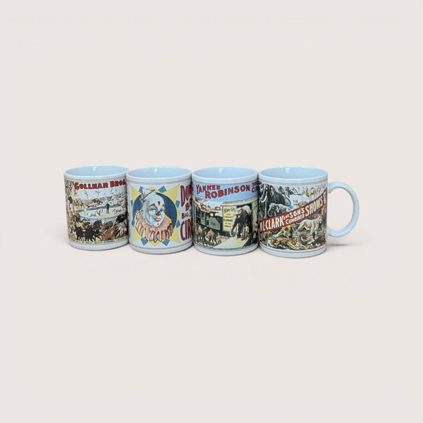 A yellow vintage box containing a set of four white ceramic mugs, each featuring a different colorful vintage circus poster illustration.