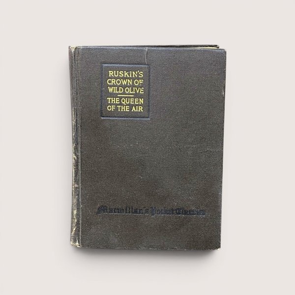 An antique dark cloth book cover titled "Ruskin's Crown of Wild Olive" in gold lettering, centered on a beige background.