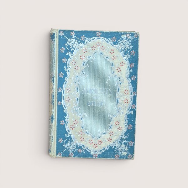 An antique blue and cream hardcover book featuring an ornate floral filigree border on the front cover