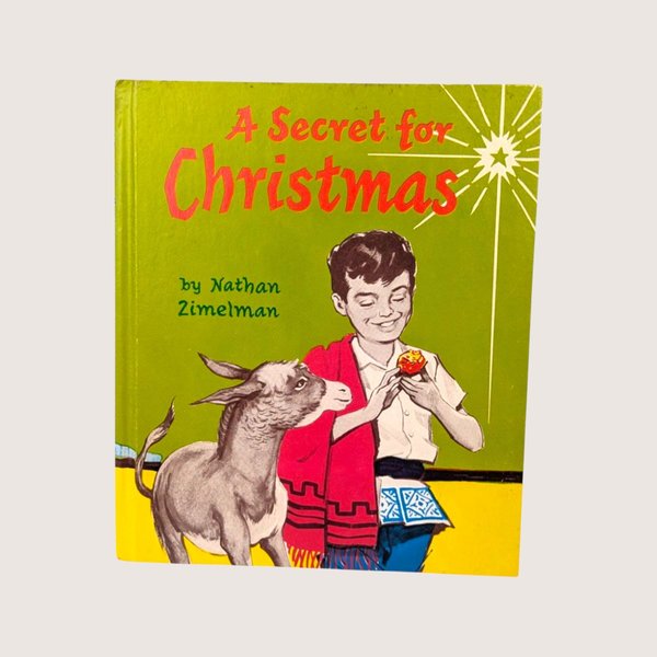 Vintage 1964 hardcover edition of A Secret for Christmas showing a boy holding a glowing stone next to a donkey.