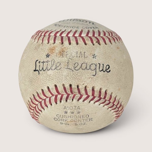 Vintage baseball with red stitching and a blue ink signature across the sweet spot, centered on a plain linen background.