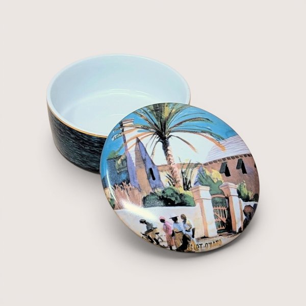 Round porcelain trinket box with a watercolor scene lid by Eliot O'Hara featuring a palm tree, centered on a plain linen background.