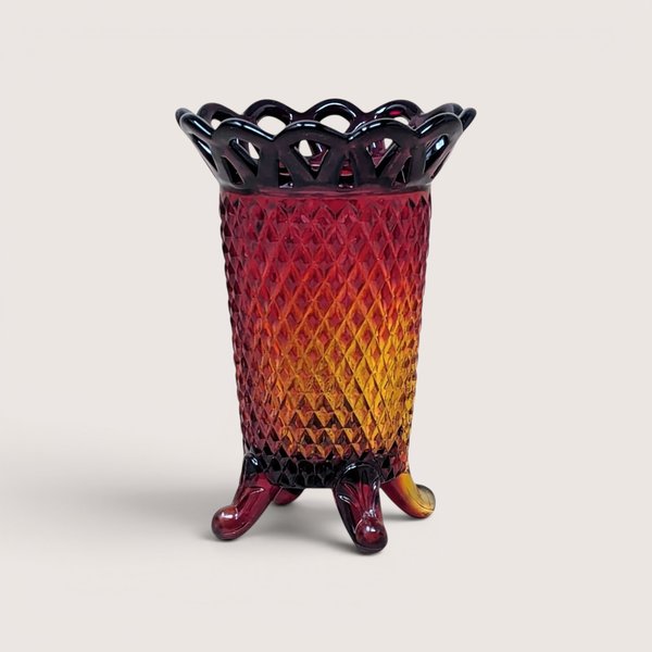 Red and amber gradient glass vase with a diamond pattern and openwork rim, centered on a plain linen background.