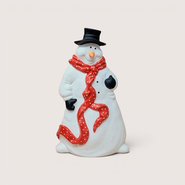 Ceramic snowman figurine wearing a black top hat and a long red scarf with white polka dots, centered on a plain linen background.