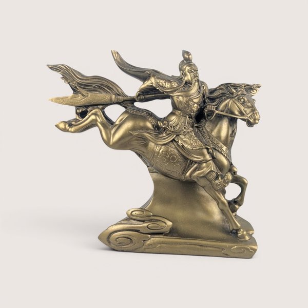 Bronze-finished statue depicting a Chinese warrior (Guan Yu) with a long beard holding a guandao pole weapon while riding a galloping horse, centered on a plain linen background.