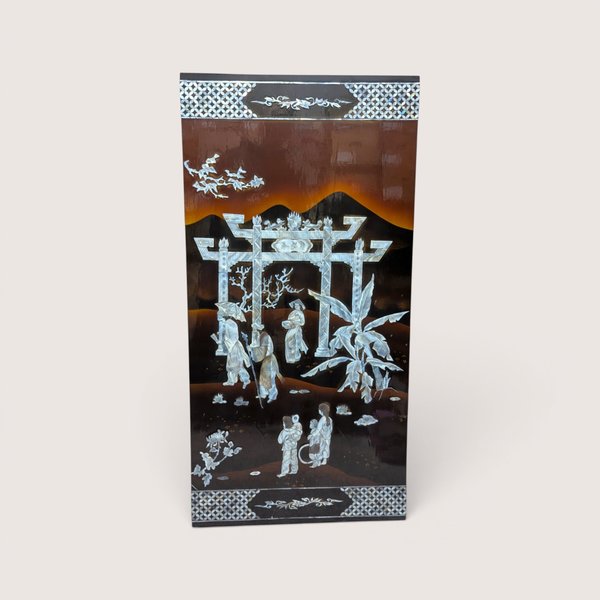 A large rectangular black lacquer wall panel featuring a detailed mother of pearl inlay scene with a grand gateway arch.