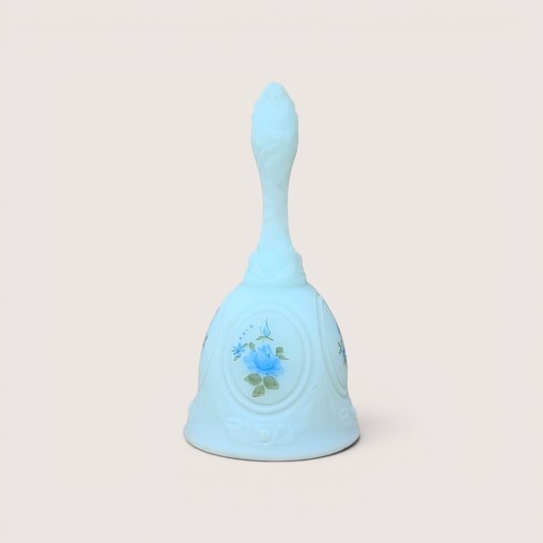 Light blue milk glass dinner bell featuring a hand-painted blue rose within an oval medallion, centered on a plain linen background.