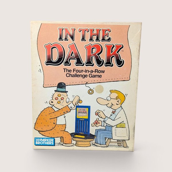 A vintage 1989 In The Dark board game box by Parker Brothers featuring a cartoon of two men playing with marbles.