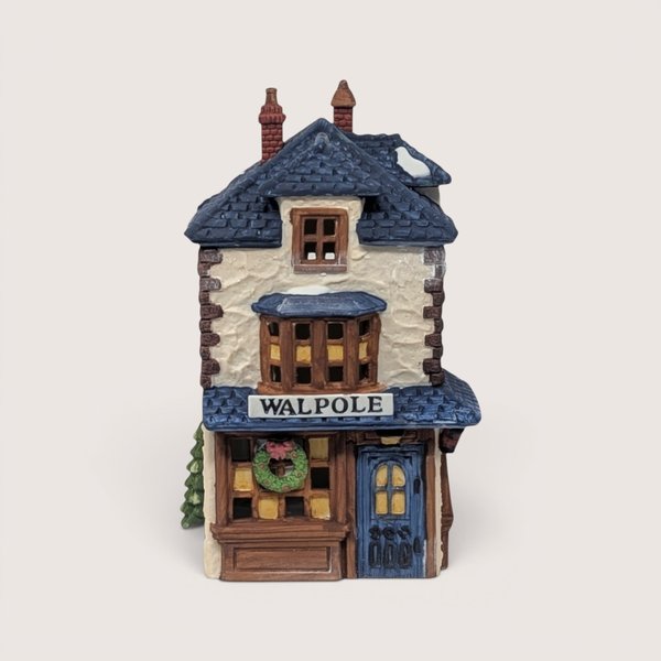 A handpainted porcelain Dept 56 Walpole Tailors shop building on a linen background