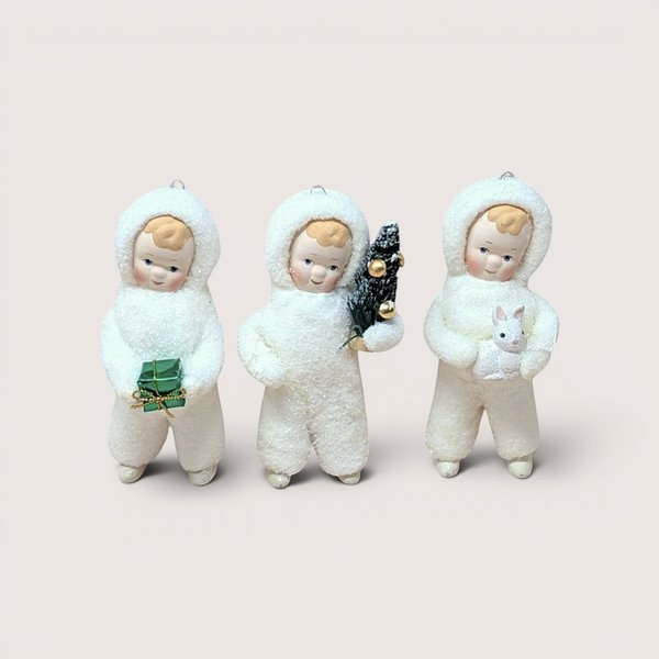 Three Department 56 Snow Angel figurines standing side by side in textured white snowsuits on a plain background