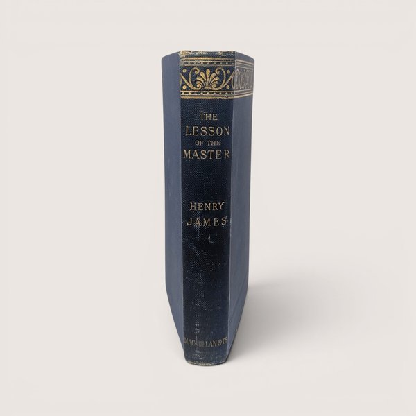 The blue spine of a vintage hardcover book featuring ornate gold gilt decorations and lettering on a plain background