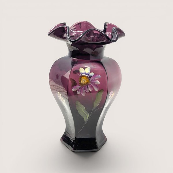 A dark purple aubergine glass vase with a ruffled rim and hand painted purple flower on a light beige backdrop