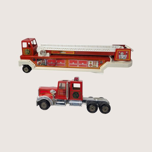 Vintage red and white Tonka hook and ladder fire truck split into its two separate cab and trailer pieces against a cream backdrop.