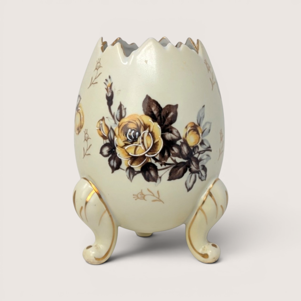 Vintage cream-colored cracked egg ceramic vase with yellow rose transfer designs standing on three gold-trimmed feet.