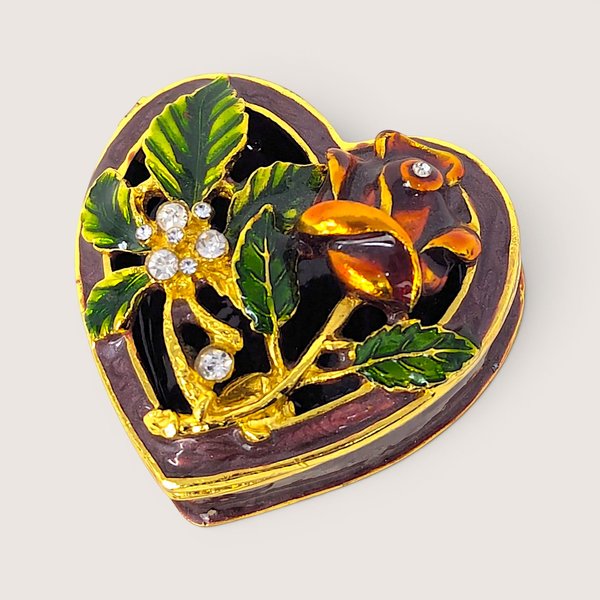 Vintage heart-shaped enameled trinket box with a gilded rose design and inset faux gemstones.