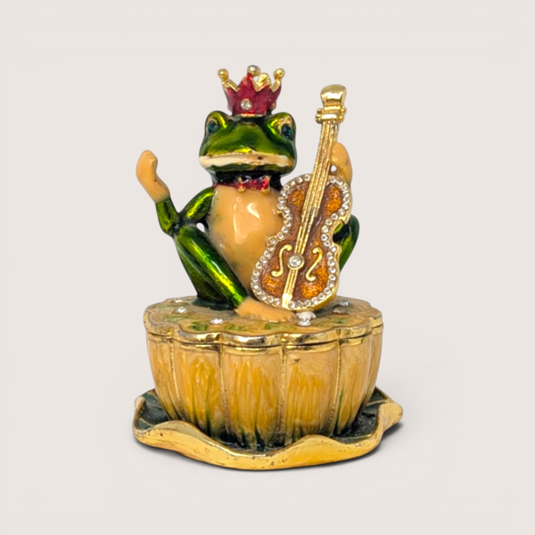 Whimsical vintage enameled metal trinket box featuring a crowned green frog holding a rhinestone-studded violin.
