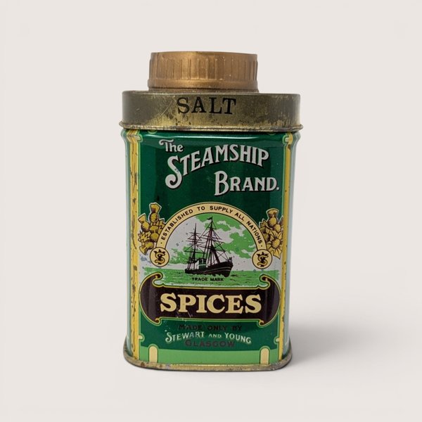 A small green vintage spice tin featuring a steamship illustration and a gold cap on a plain white background