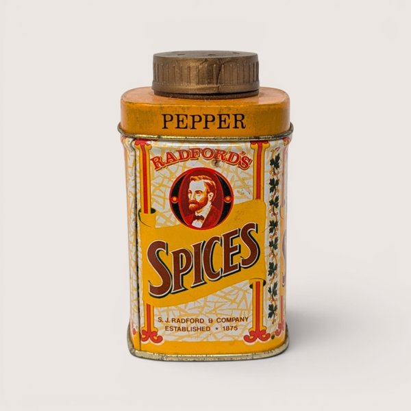 A small yellow vintage spice tin featuring a man portrait and a gold shaker cap on a plain white background