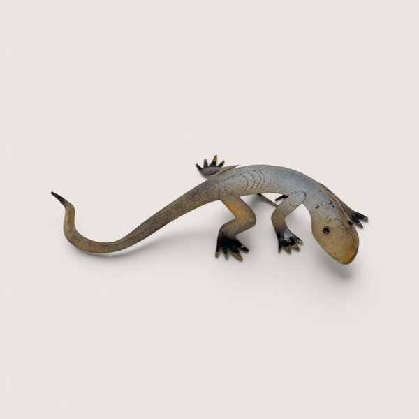 Vintage stylized metal lizard wall sculpture with a curved tail and rusted finish against a light backdrop.