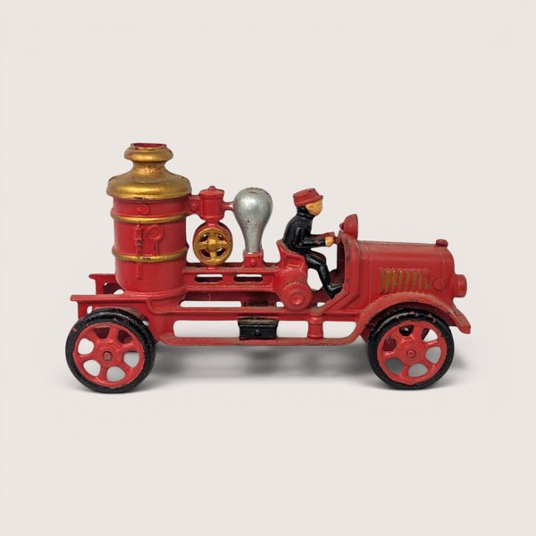 Vintage red Hubley cast iron pumper fire engine toy with gold boiler tank and cast iron driver figurine.