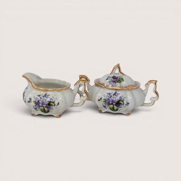 Vintage Napco porcelain creamer and lidded sugar bowl set with purple violet flowers and gold handles and trim.